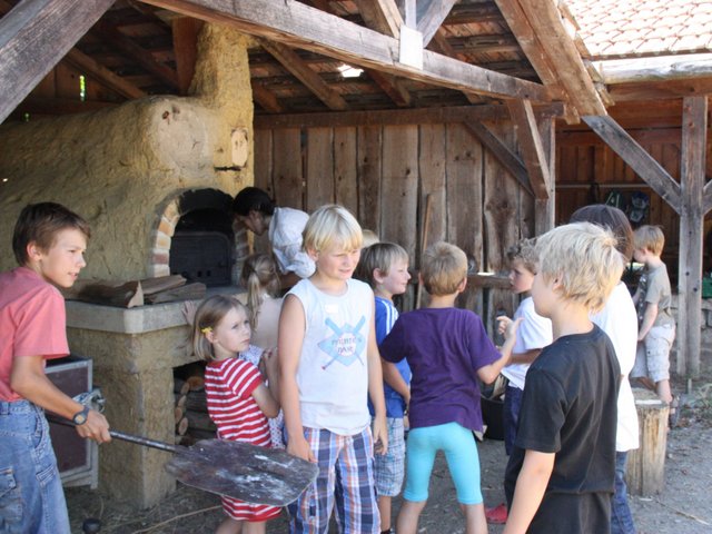 Eine Gruppe Kinder vor einem Steinofen